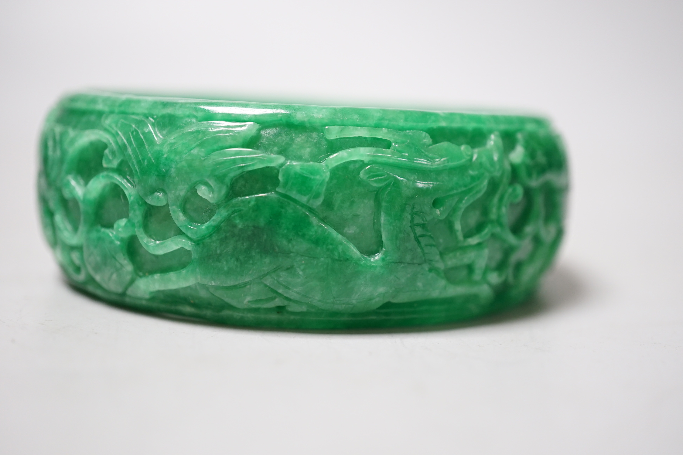 A Chinese carved jadeite bangle, 8.5cm diameter
